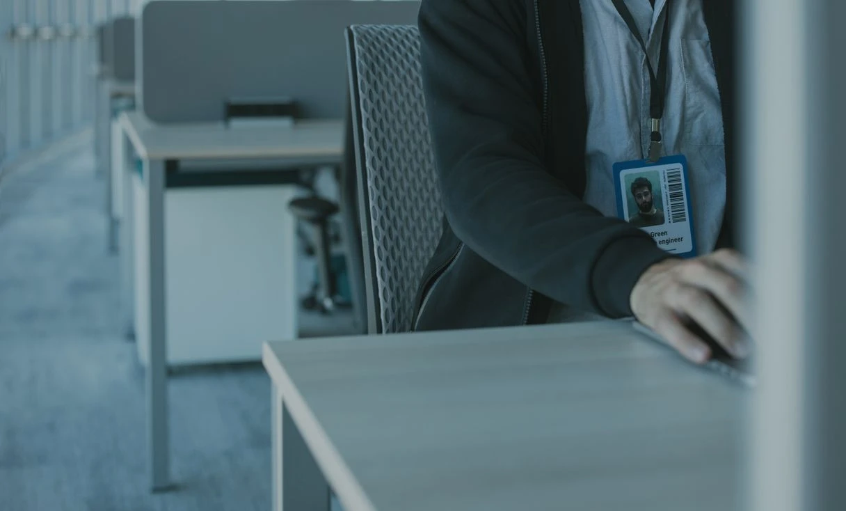 Homem trabalhando em um escritório usando crachá, representando: Funcionário saiu e o acesso continua ativo: o risco que ninguém revoga
