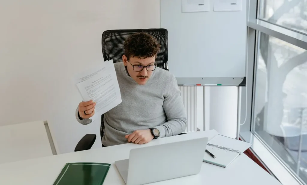 Homem de óculos trabalhando em laptop no escritório, representando: E-mail parado: o problema que sua empresa só percebe quando já perdeu dinheiro