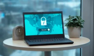 Laptop com ícone de cadeado na tela em mesa de escritório, representando: Antivírus/Defender bloqueou seu sistema? Volte hoje