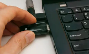 Mão inserindo token USB em notebook, representando: Certificado digital venceu? Como voltar a emitir hoje