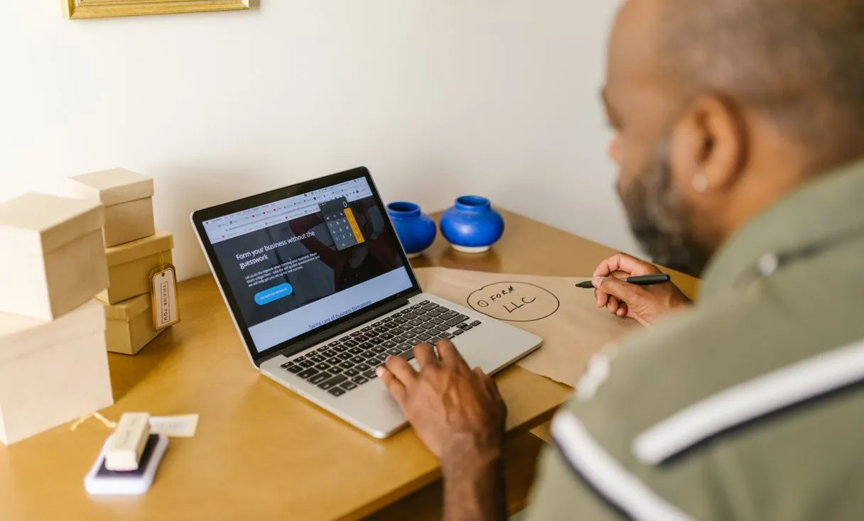 Empresário no computador conferindo site e configurações representando: Domínio e e-mail da empresa: como evitar parar por causa do DNS