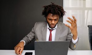 Empresário frustrado ao computador no escritório, representando: E-mail corporativo fora do ar? Como arrumar o DNS hoje
