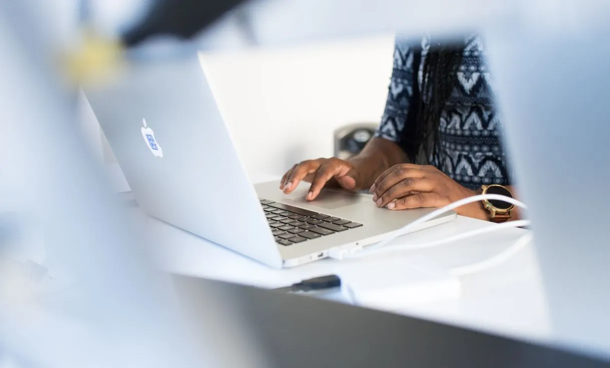 Mulher digitando em notebook em mesa de escritório representando: Office 365 não ativa? Como resolver sem travar a equipe
