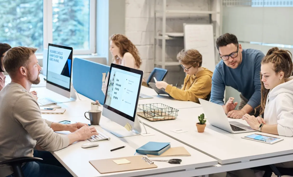 Equipe colaborando em frente ao computador representando: Unidade de rede cai? Como padronizar e não travar a equipe