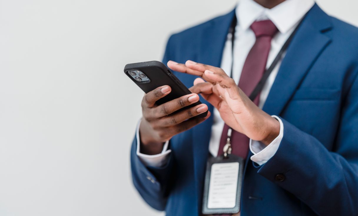 Profissional de terno usando smartphone no escritório, representando: Senha no WhatsApp? Como parar o risco hoje