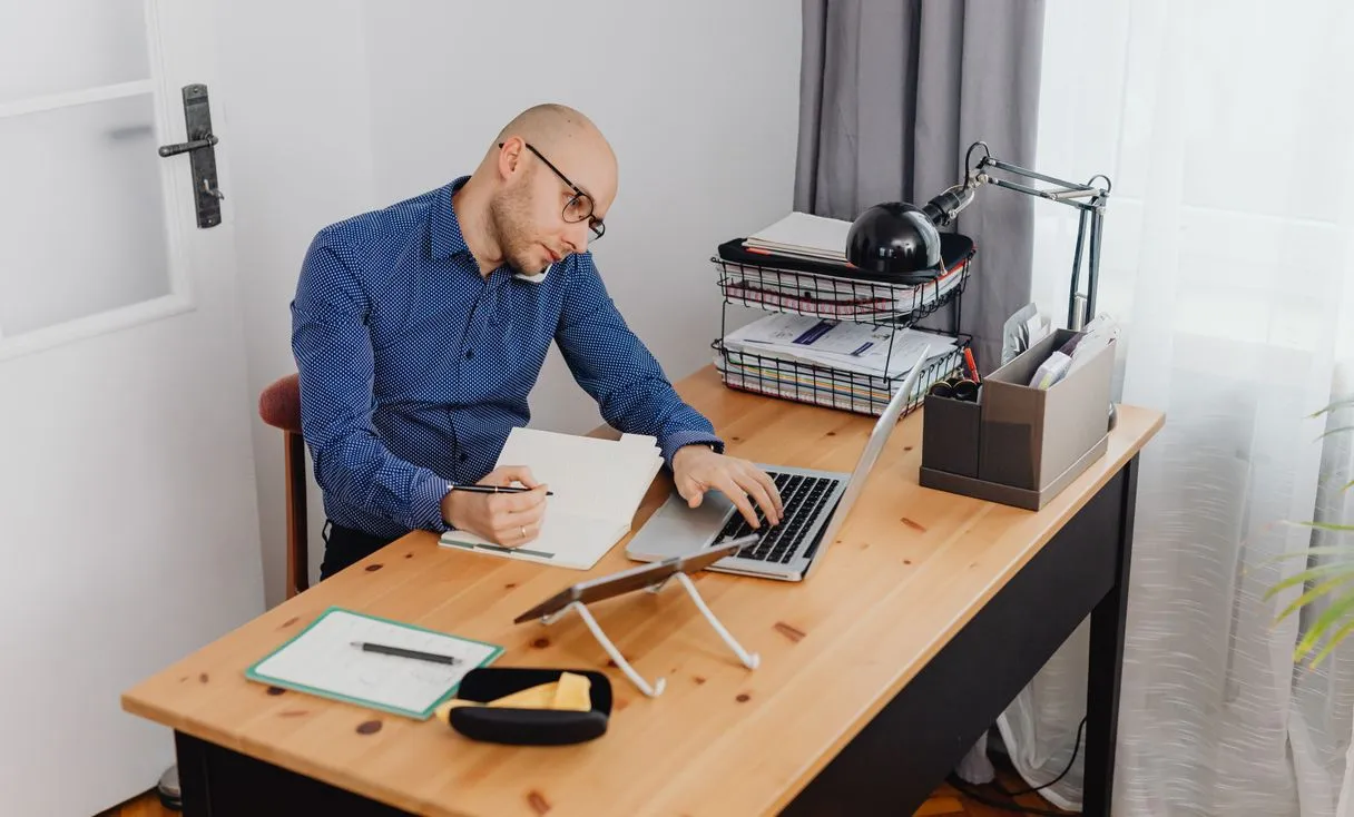 Homem trabalhando com notebook em mesa de escritório em casa, representando: Acesso remoto ou VPN falhando na empresa? Veja o que fazer antes de abrir chamado