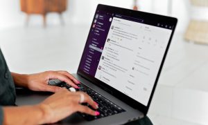 Mulher digitando no notebook com aplicativo de mensagens aberto, representando: E-mail da empresa vai para spam? Corrija SPF, DKIM e DMARC
