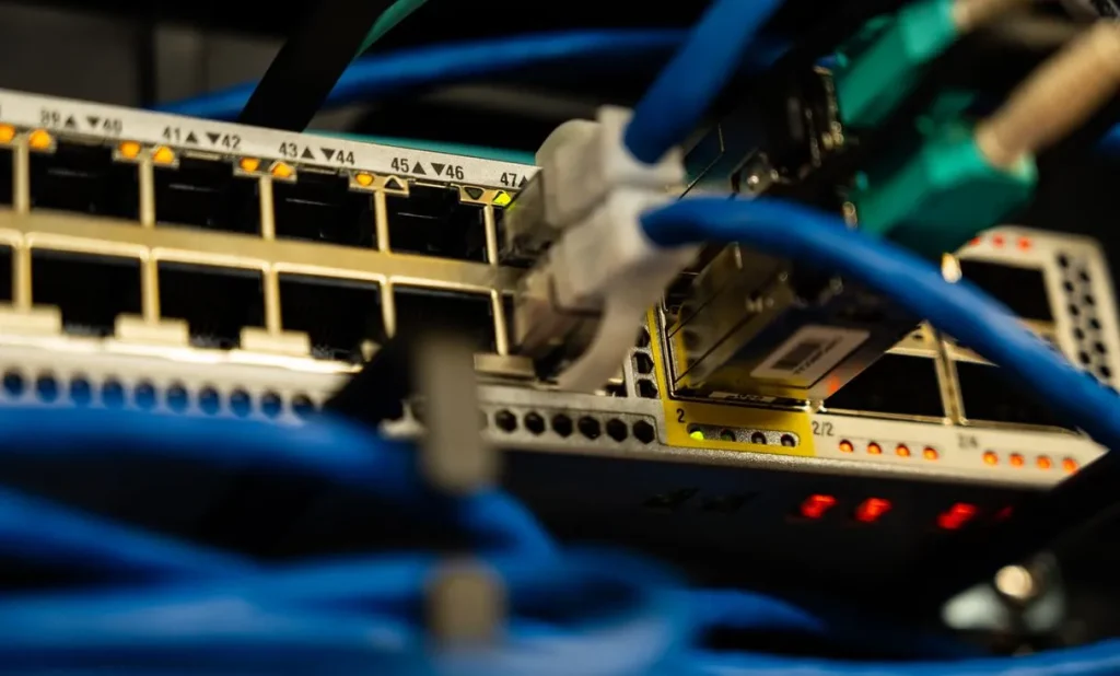 Close de switch com cabos de rede plugados representando: VPN instável na empresa? Como parar a queda do trabalho remoto
